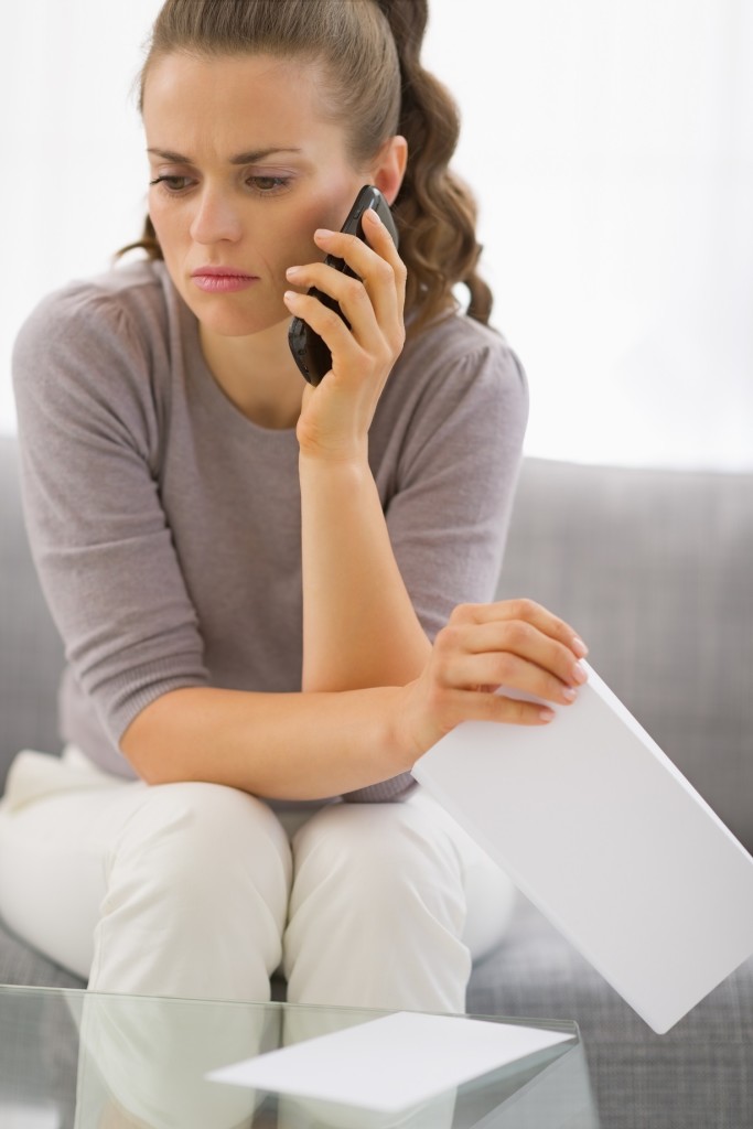 Concerned young woman with letter and phone