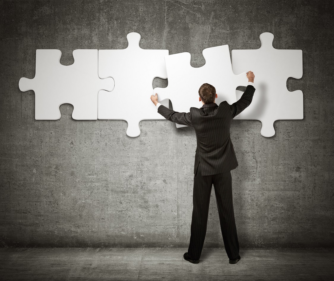 Businessman making a puzzle on the wall