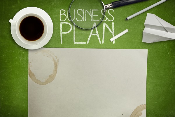 Business plan concept on green full frame blank blackboard with coffee cup. empty paper and magnifying glass