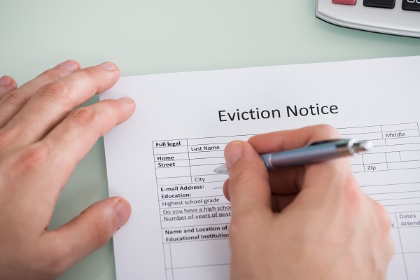 Close-up Of Person Hand Filling Eviction Notice Form